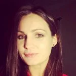 A woman with long dark hair and light skin, looking at the camera with a slight smile.