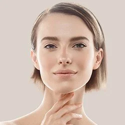 Close-up of a young woman with short hair and clear skin, gently touching her chin with her hand.