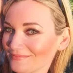 Close-up of a smiling woman with blonde hair and blue eyes, wearing a headband.