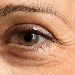 Close-up of a person's eye with visible wrinkles and some makeup.