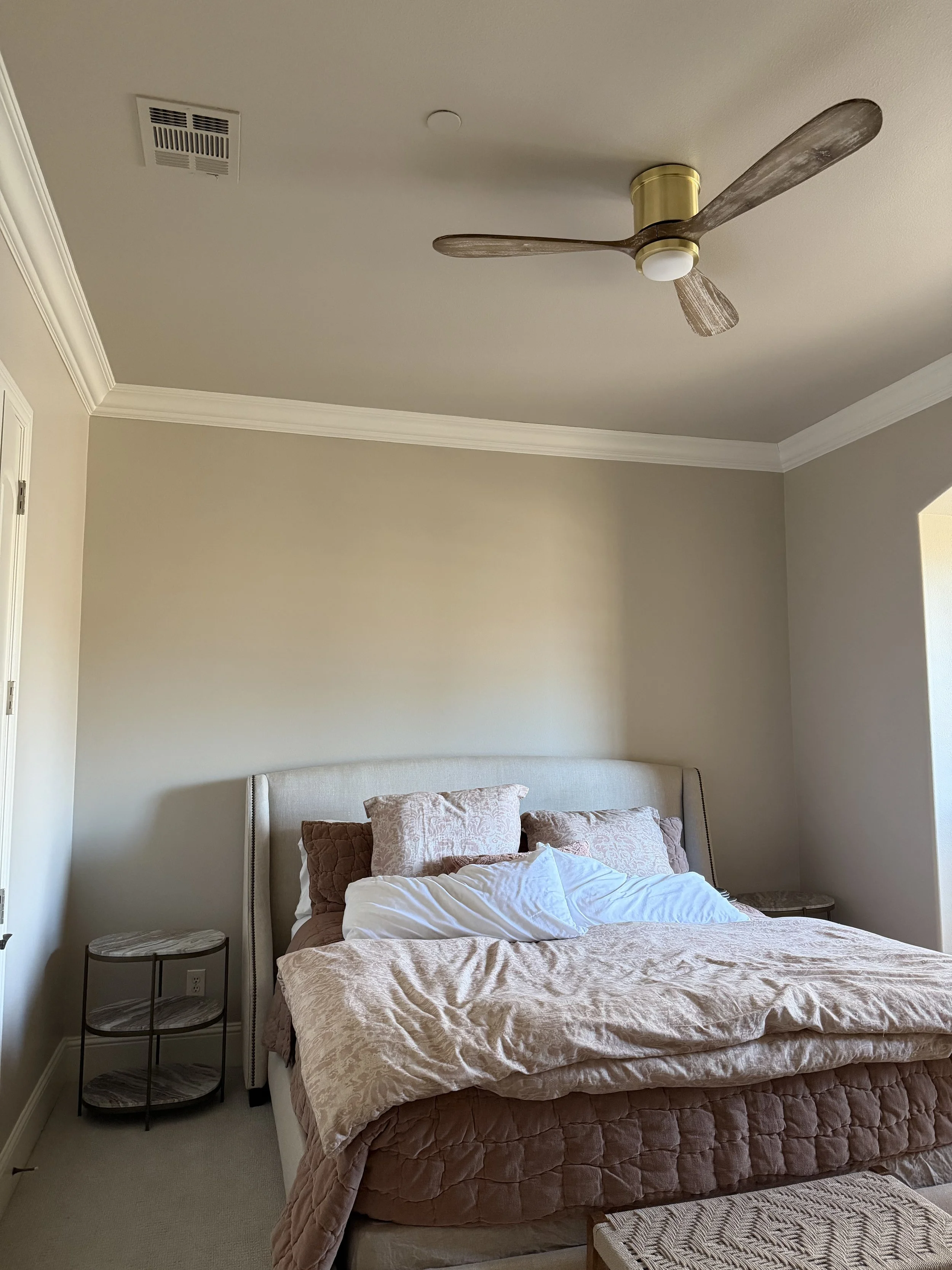 A bedroom with a bed, side tables, and a ceiling fan.