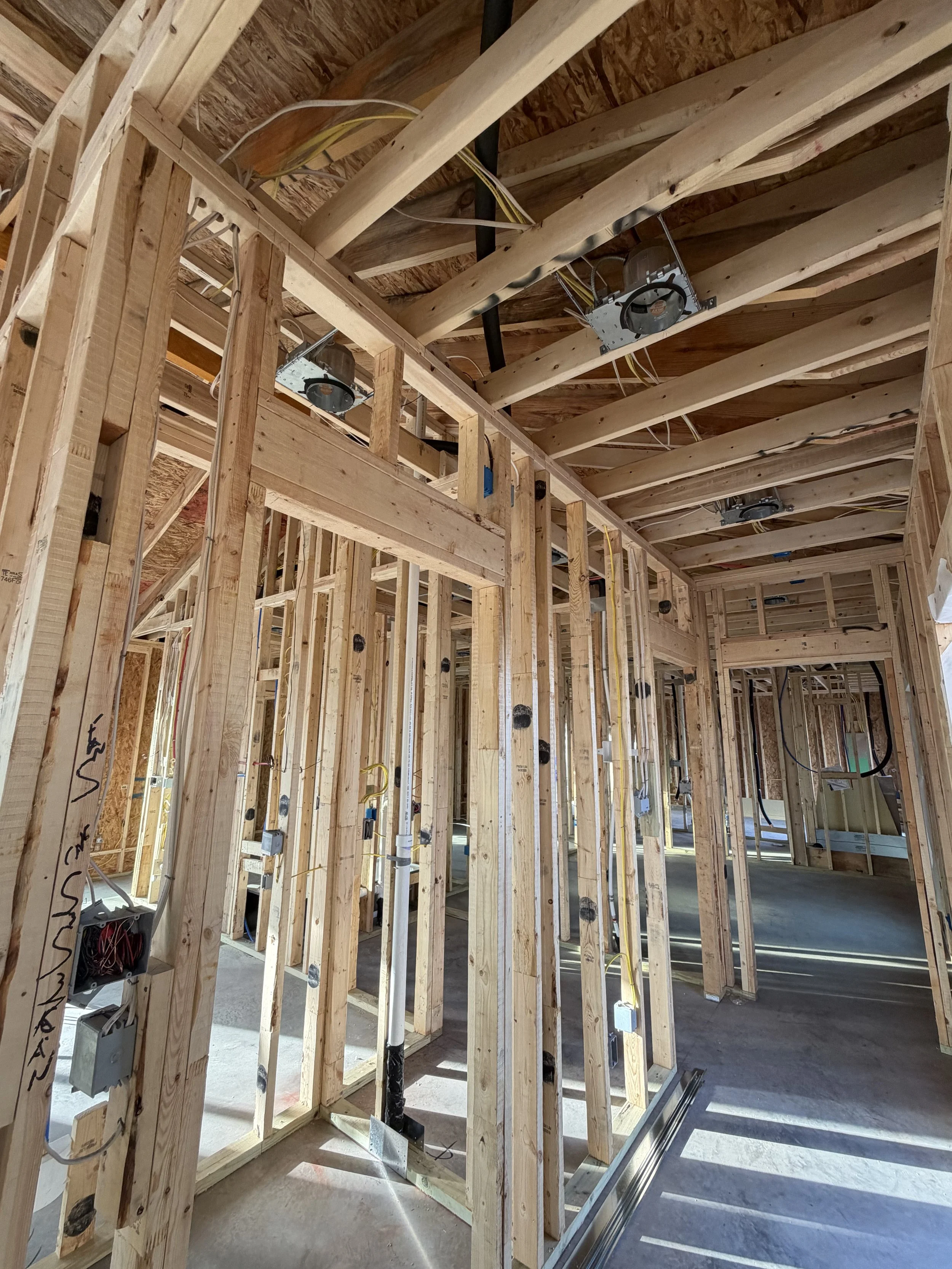 Interior view of a house under construction showing wooden framing and electrical wiring.