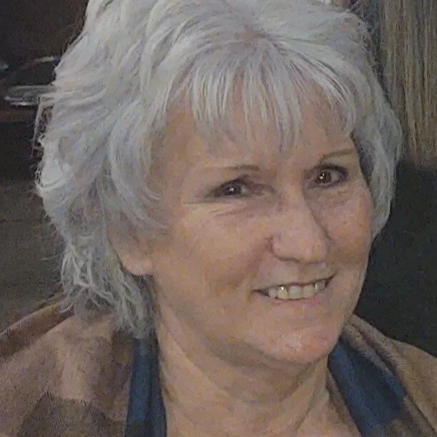 A smiling older woman with short, curly gray hair.