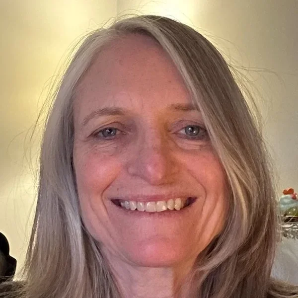 Close-up of a woman with long blonde hair and blue eyes smiling at the camera.