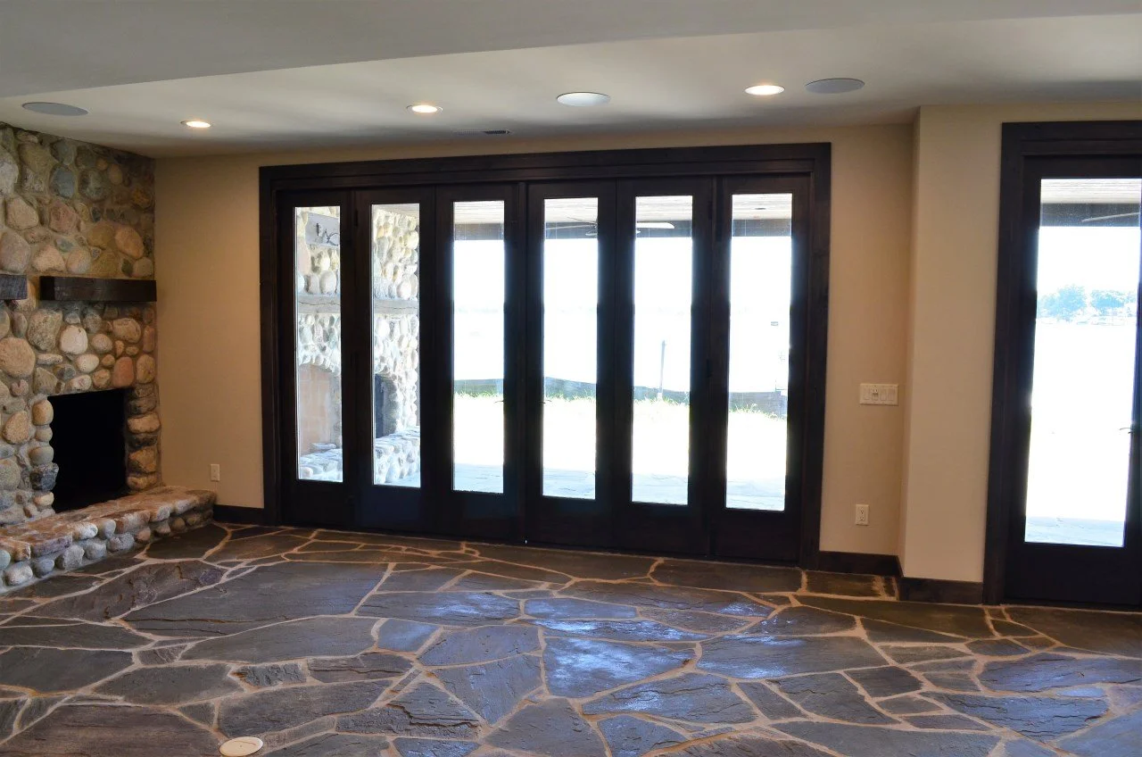 Living room with stone fireplace, large glass sliding doors, and stone tile flooring.