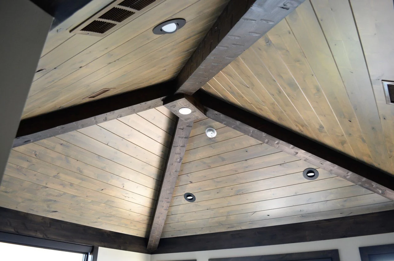View of a wooden vaulted ceiling with recessed lighting and air vents.