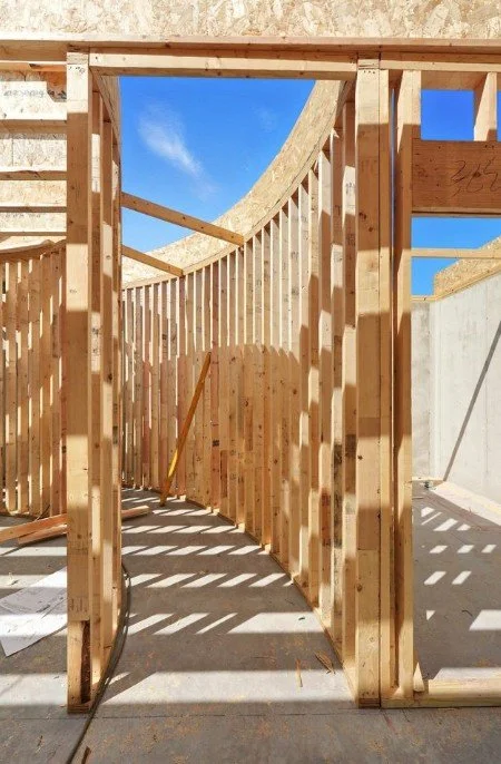 Construction site with wooden frame structure and blue sky with clouds in the background.
