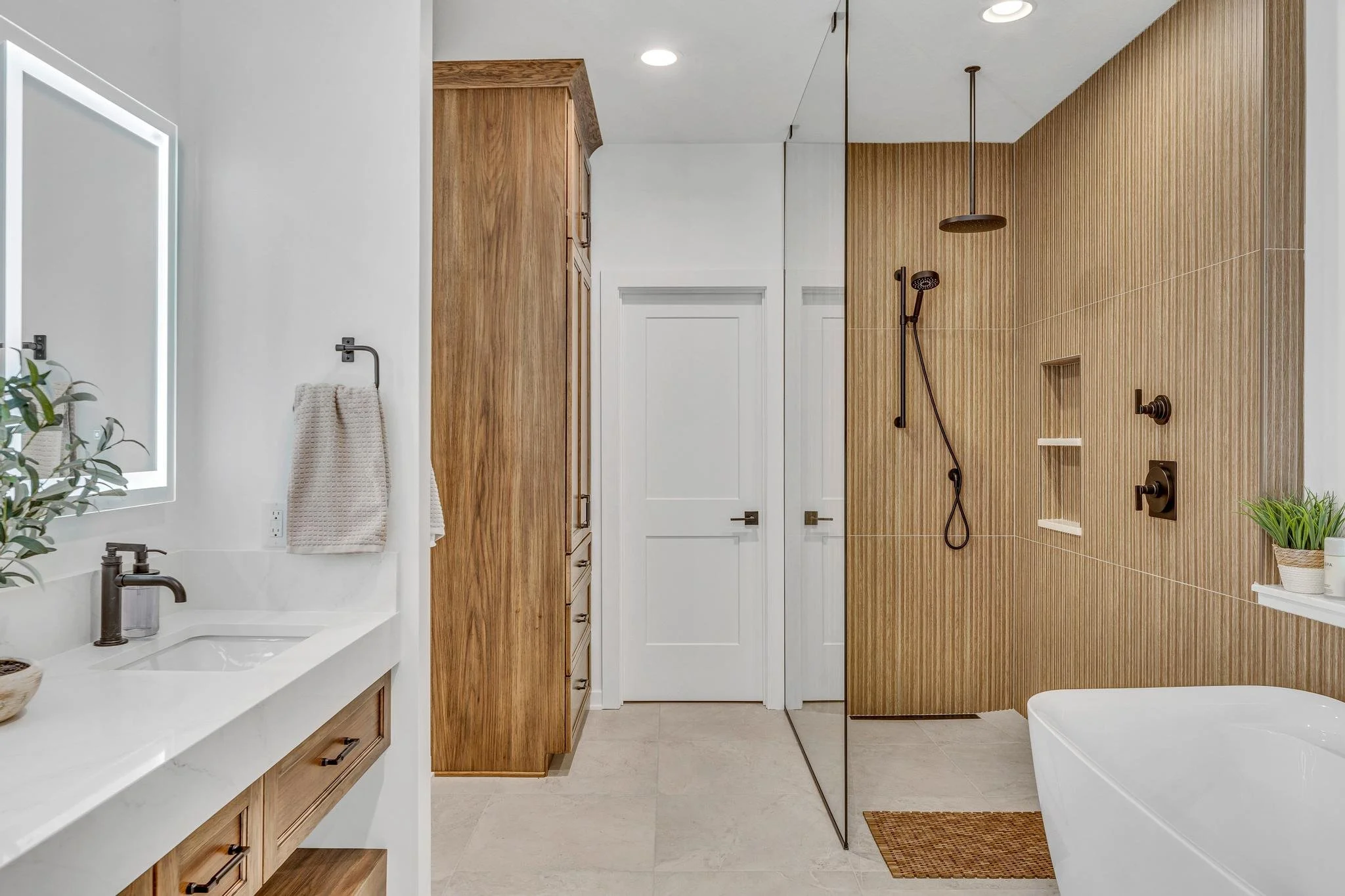 Modern bathroom with a white vanity, wooden cabinets, and a shower area with a wooden wall and a black showerhead.