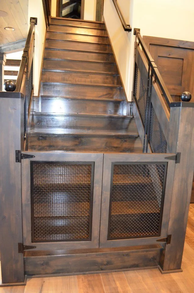 Wooden staircase with black metal railings and mesh panels, leading to an upper level in a home interior.