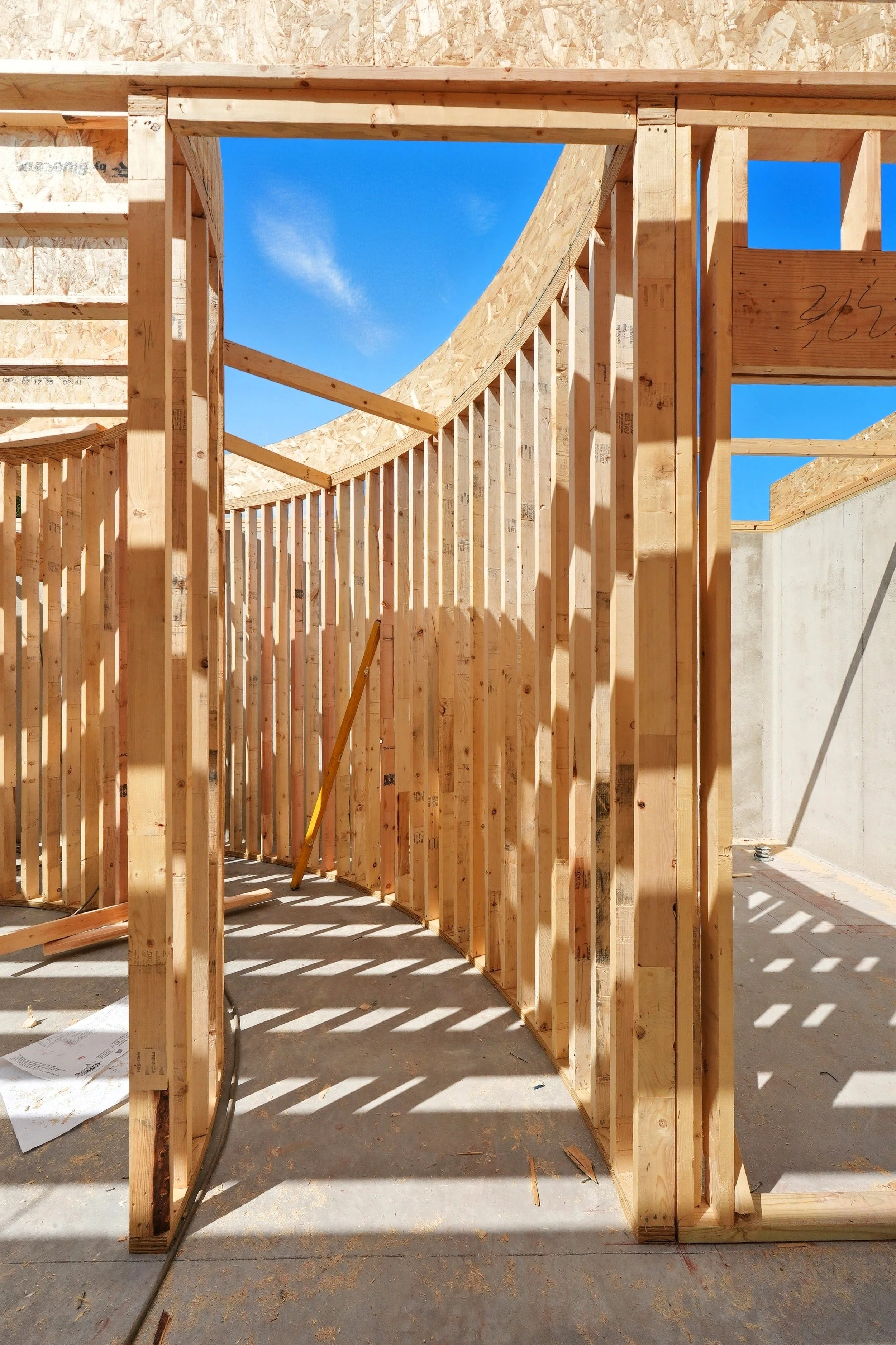 Wooden framing of a building under construction with blue sky visible through the opening.