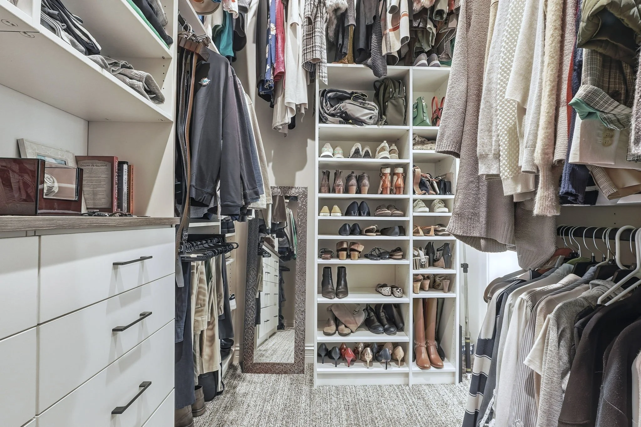 A walk-in closet with organized shelves and hanging clothes, shoes, and accessories.