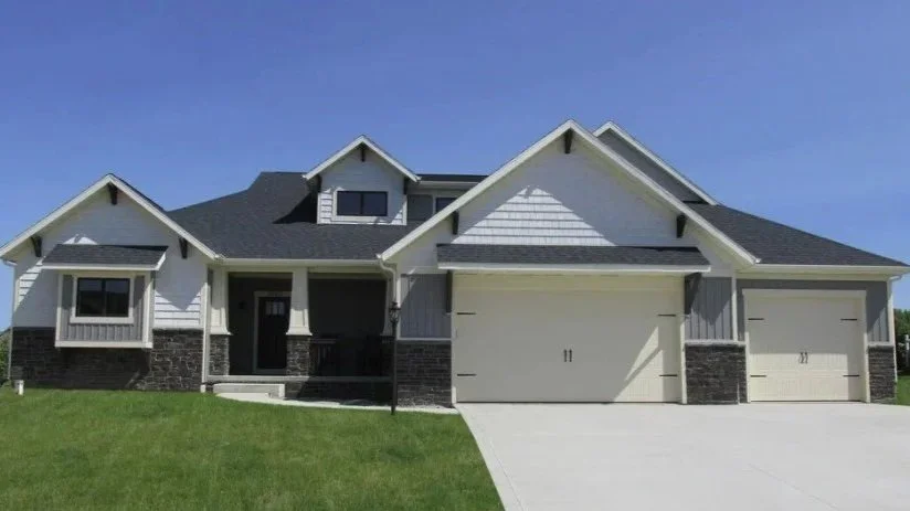 Front view of a modern two-story house with a large driveway, white exterior, dark roof, and multiple windows.