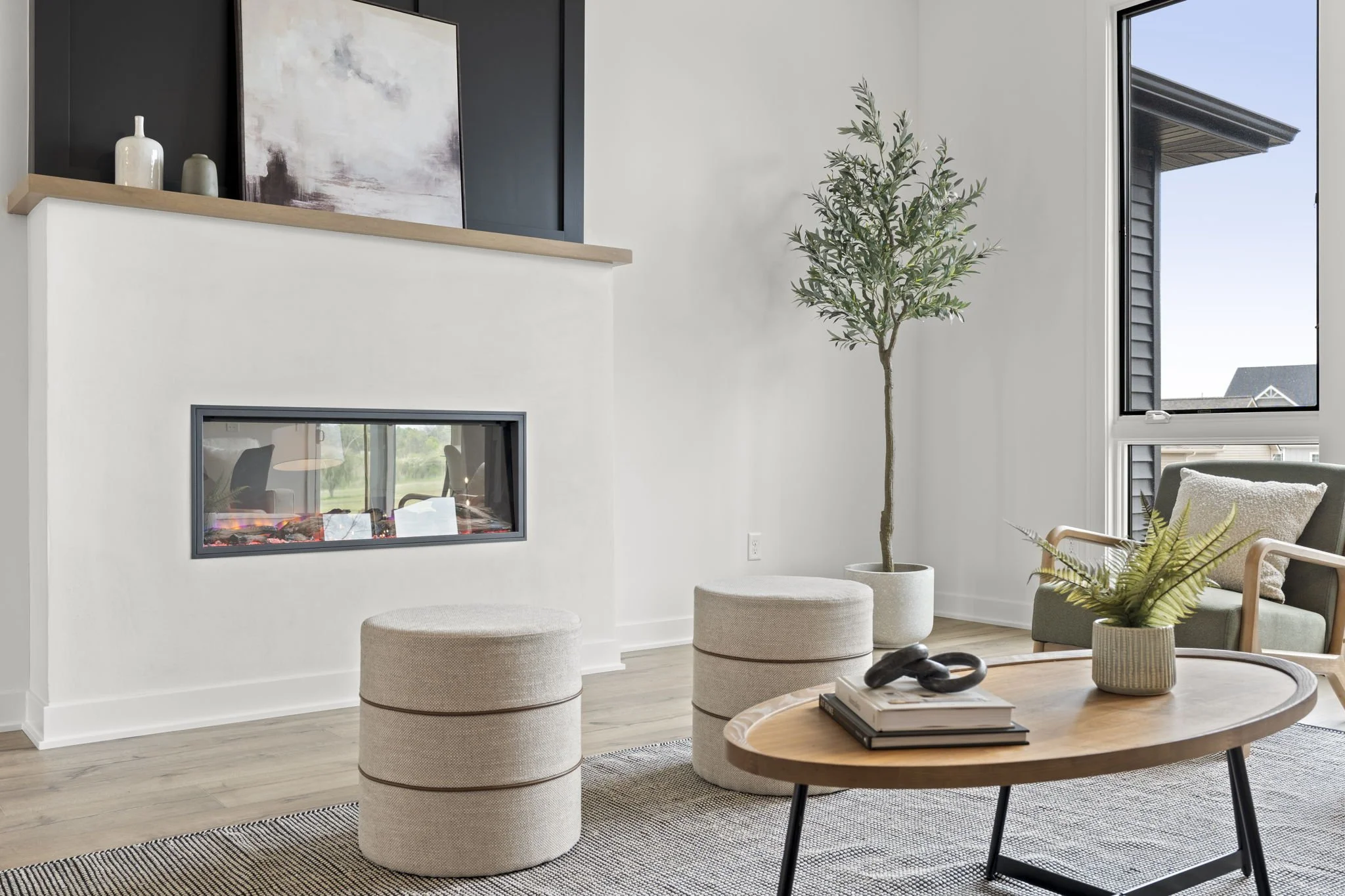 Modern living room with a fireplace, potted plant, armchair, wooden coffee table, and decorative items.