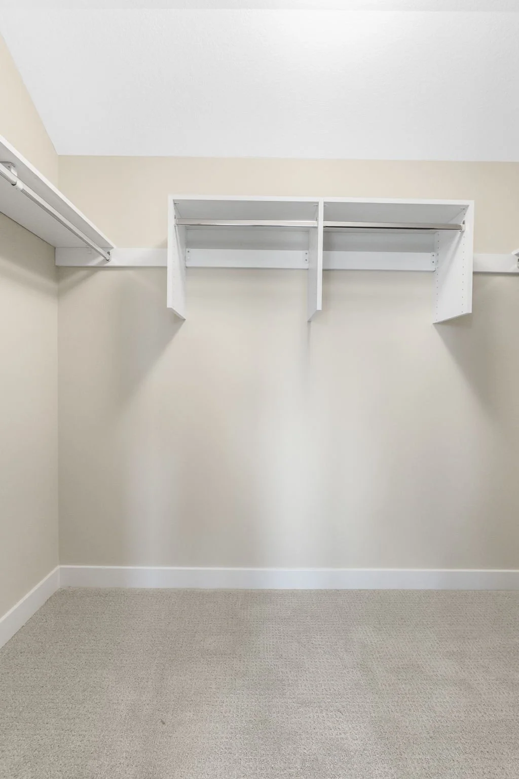 Empty walk-in closet with white shelves and beige carpet.