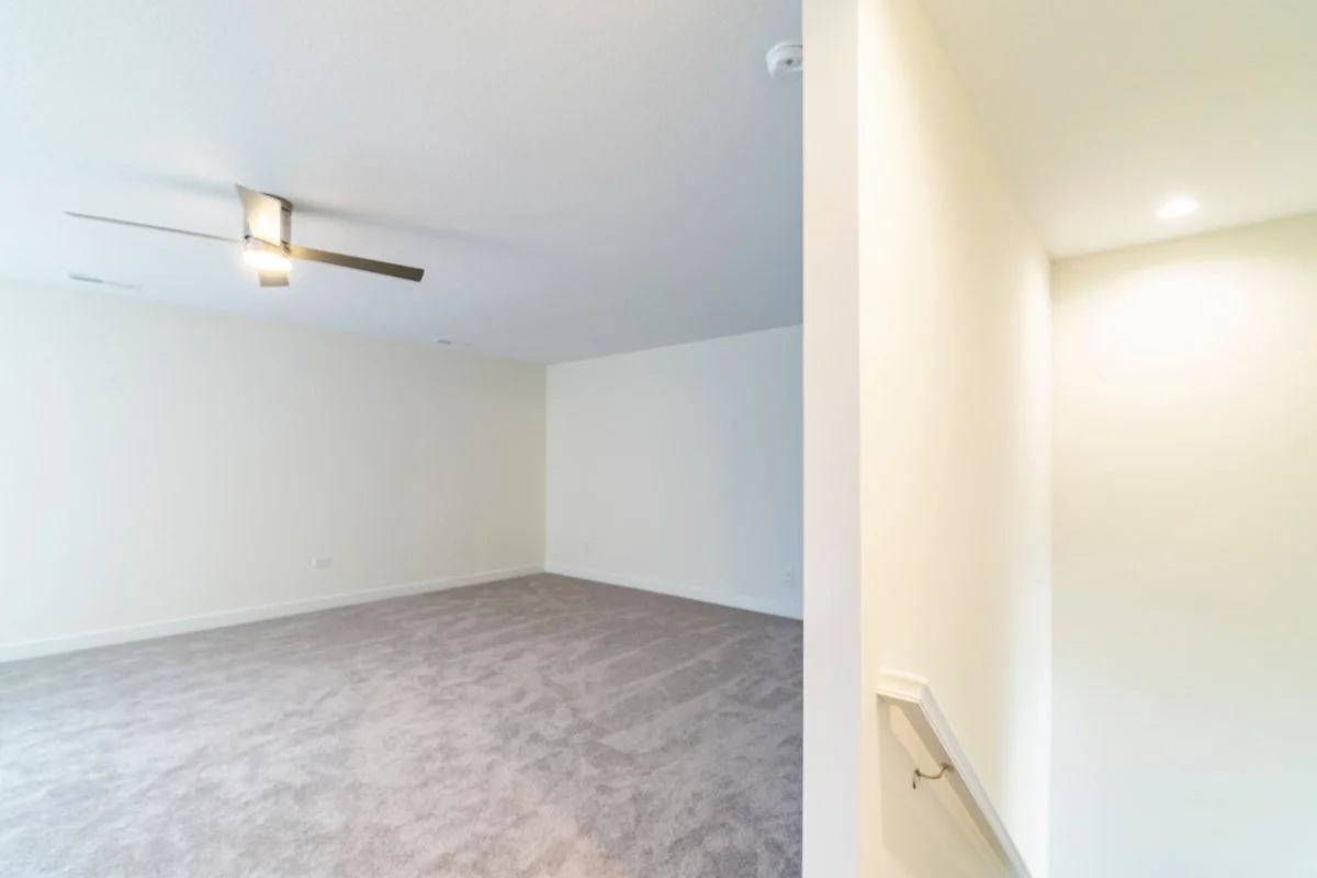 Empty room with light-colored walls, gray carpet, a ceiling fan, and recessed lighting.