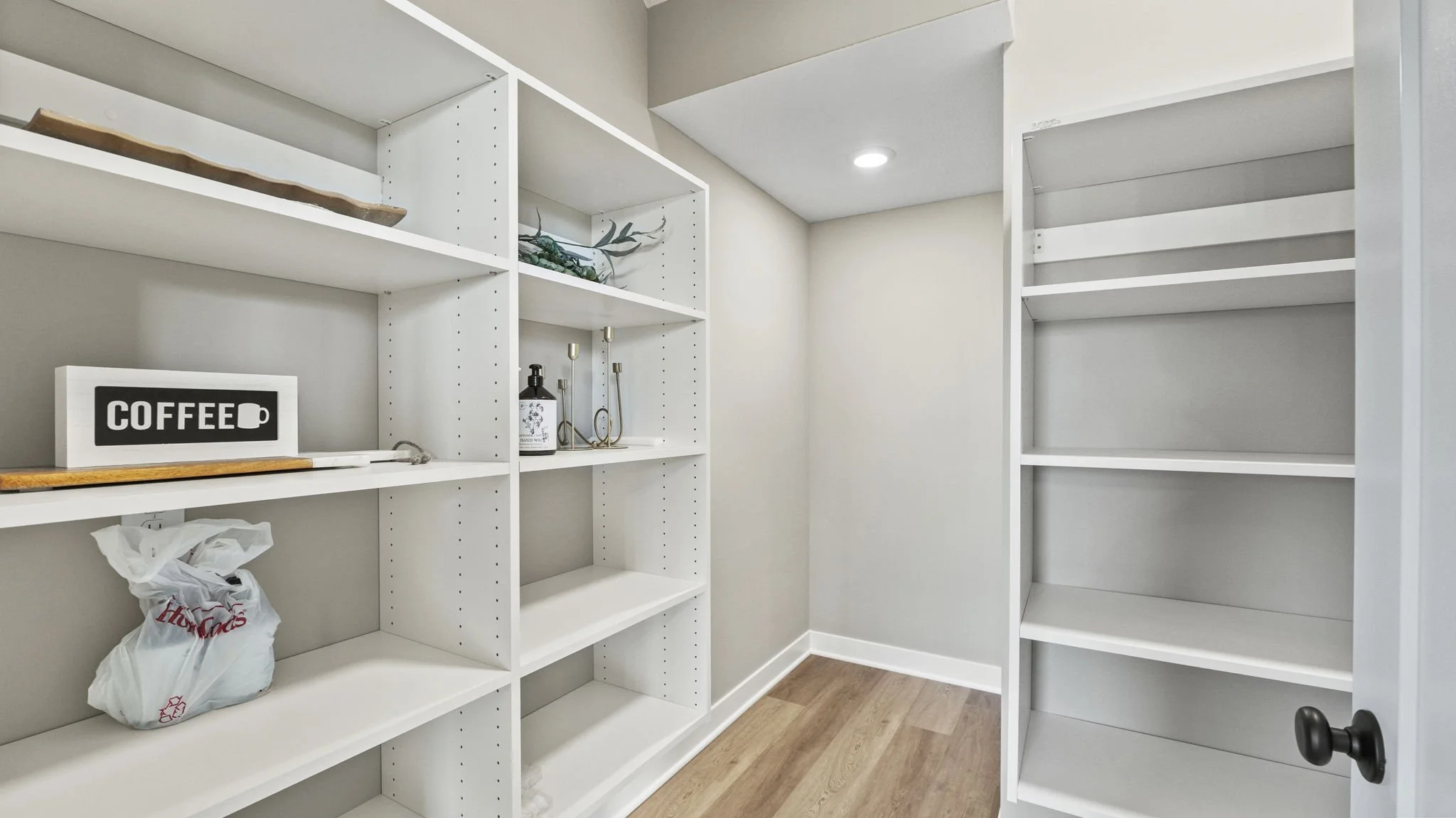 Empty white built-in shelves in a room with light wood flooring and beige walls.