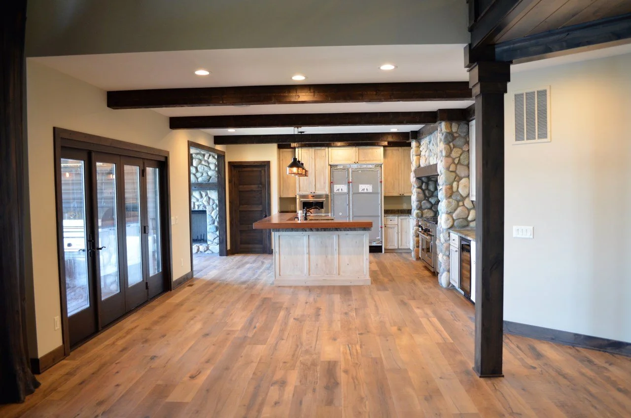 Open-concept kitchen with wooden floors, stone fireplace, and sliding glass doors leading outside.
