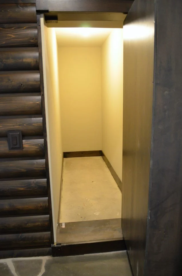 Empty closet or small storage space with yellow walls, a wooden floor, and a light source at the top.