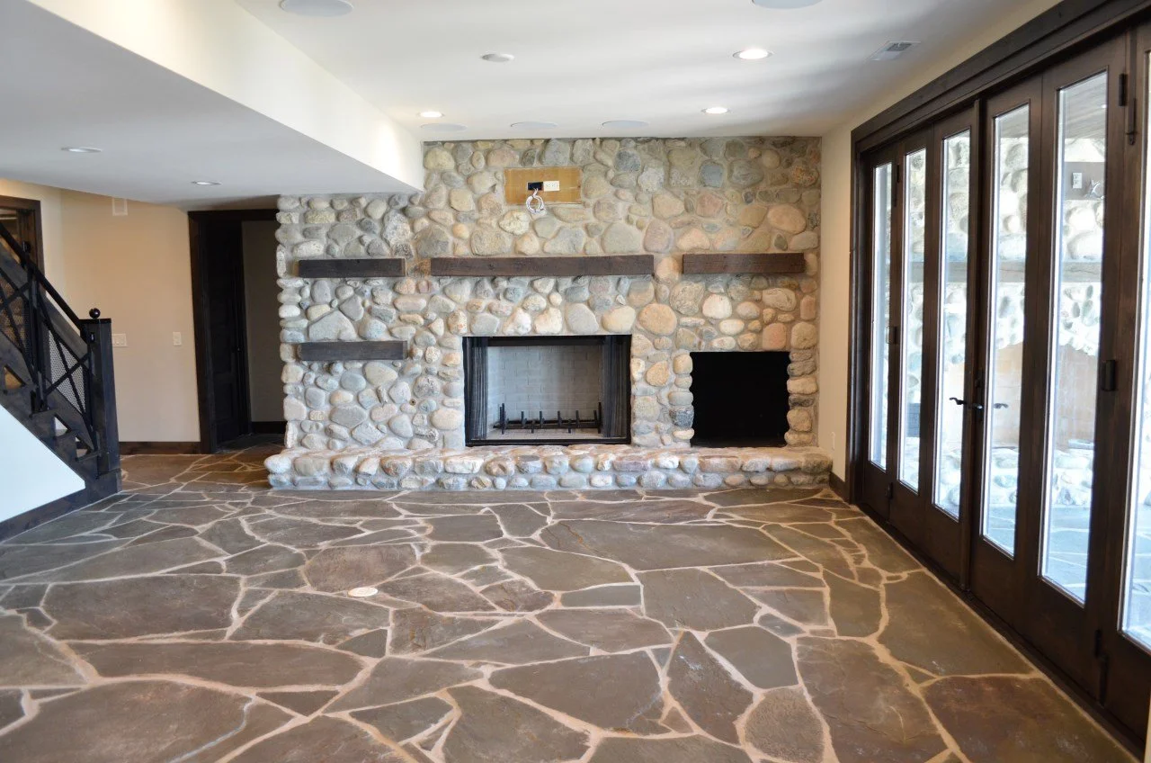 Interior living room with stone fireplace and large glass doors.