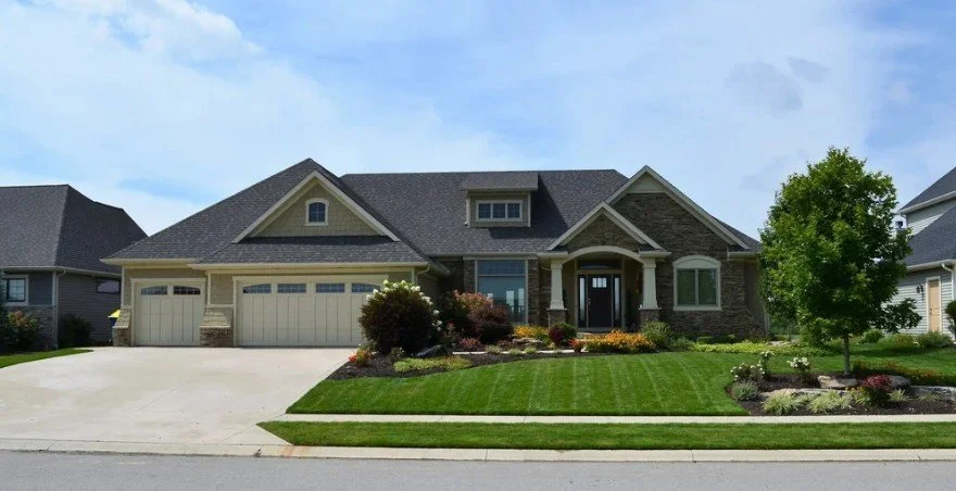 Front view of a large two-story suburban house with a manicured lawn and landscaping