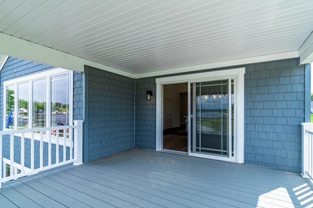 Empty outdoor balcony or screened porch with sliding glass door, blue exterior walls, white railing, and ceiling.