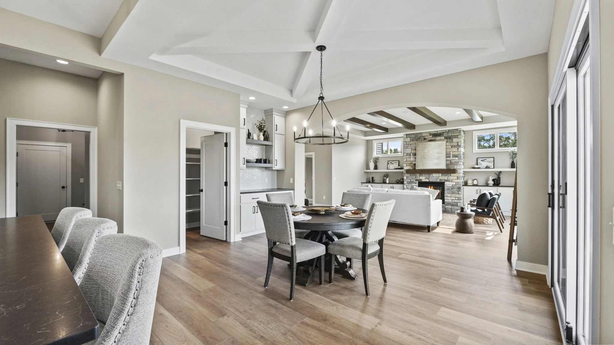 Modern living and dining room with hardwood floors, white walls, a fireplace with stone surround, and large windows