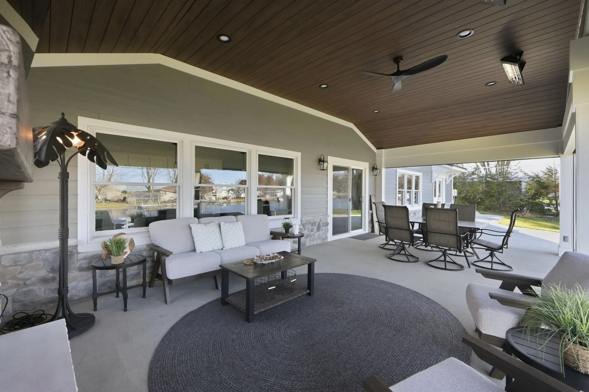 Covered outdoor patio with seating and dining area, large windows, and a ceiling fan.