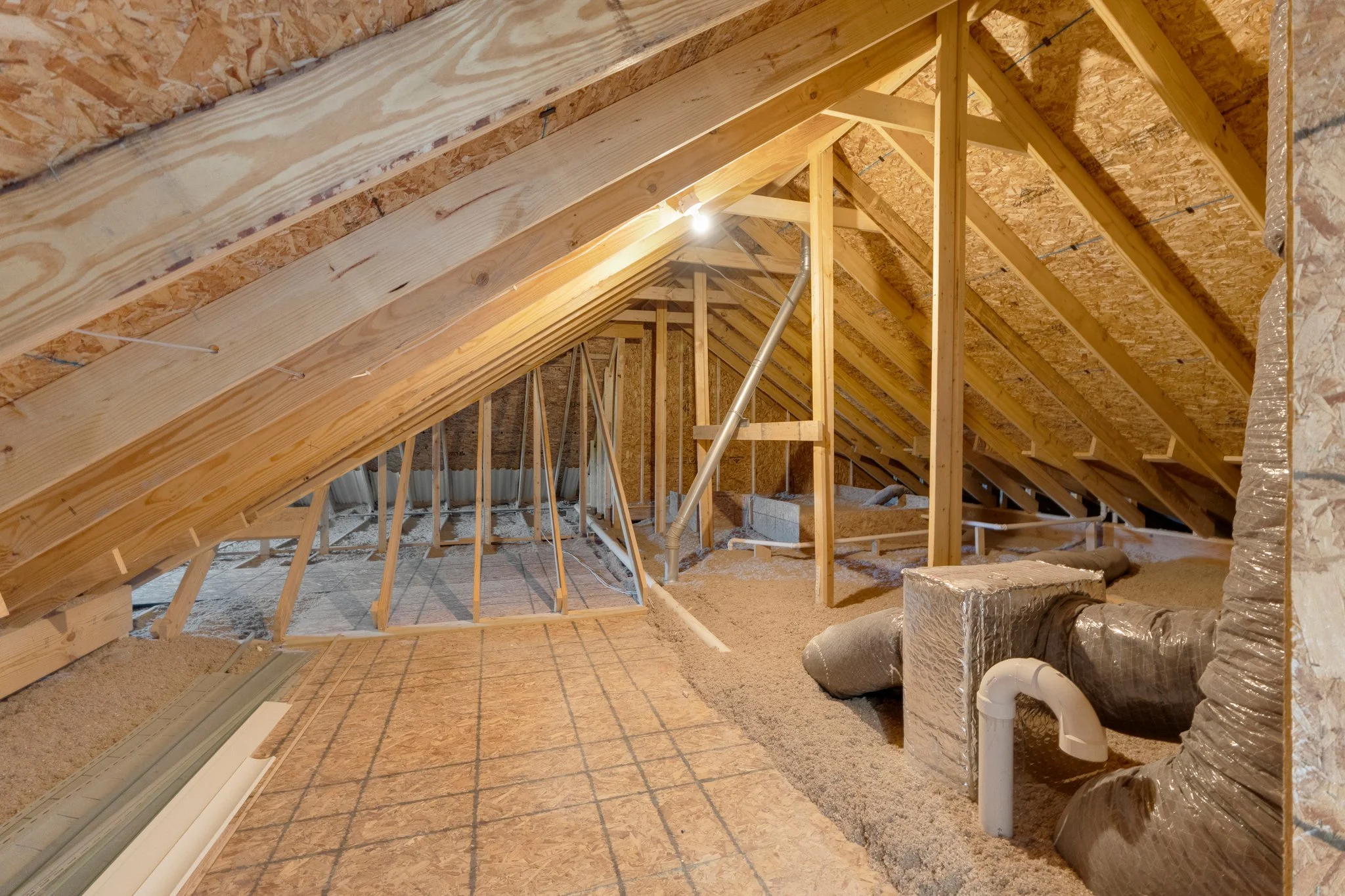 Attic space under construction with wooden framing, insulation, and ductwork visible.