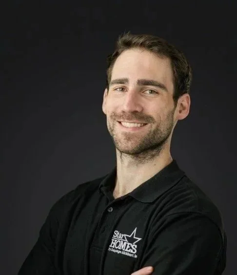 A smiling man wearing a black polo shirt with a logo that reads 'Star Homes' on a dark background.