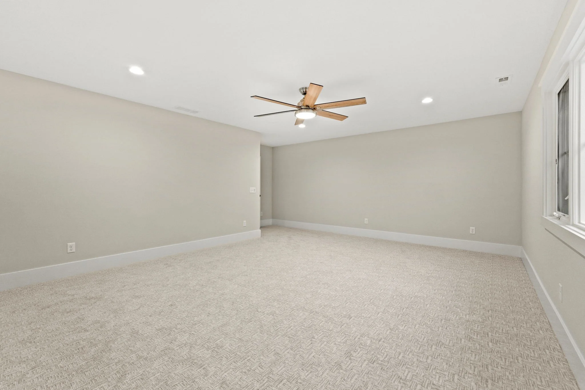 Empty room with beige carpet, light-colored walls, a ceiling fan, and a window.