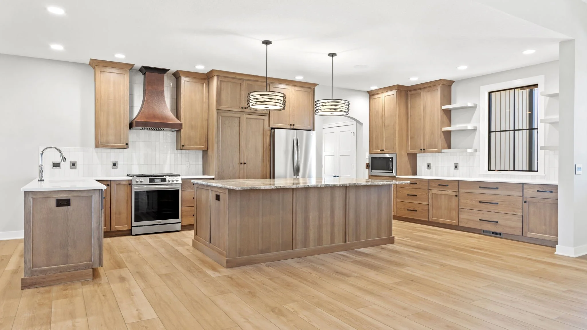 Modern kitchen with wood cabinets, white countertops, stainless steel appliances, and a kitchen island with pendant lighting.