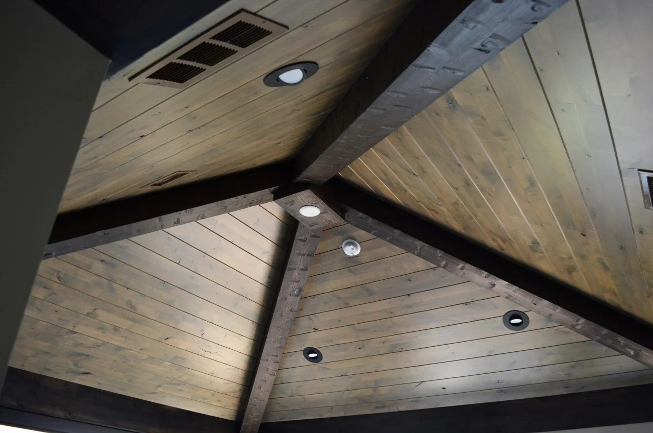 Ceiling made of wood panels with recessed lights and a smoke detector.