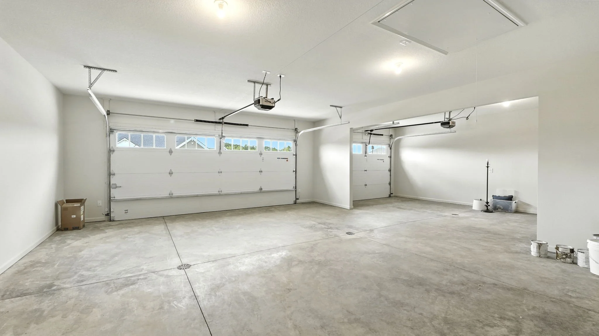 Empty two-car garage with white walls, concrete floor, and two overhead garage door openers.