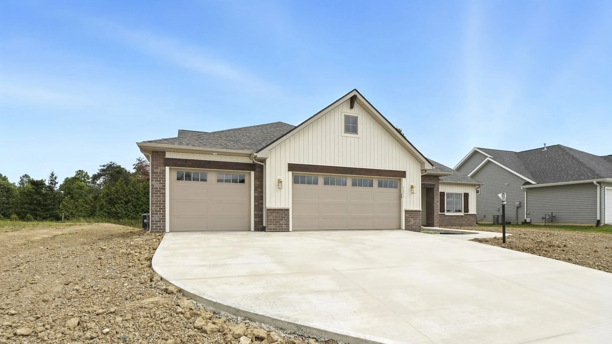 Newly built house with a two-car garage, concrete driveway, and front yard grassy area.