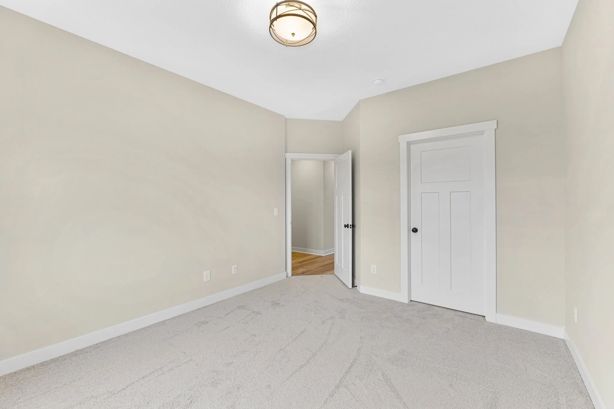 Empty room with beige walls, white trim, carpeted floor, and a ceiling light fixture.