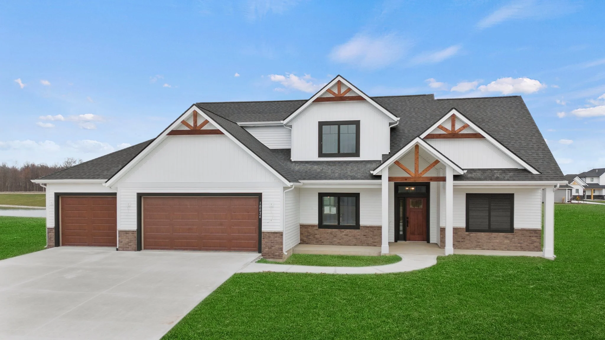 Front view of a large modern house with gray siding, stone accents, and a two-car garage.