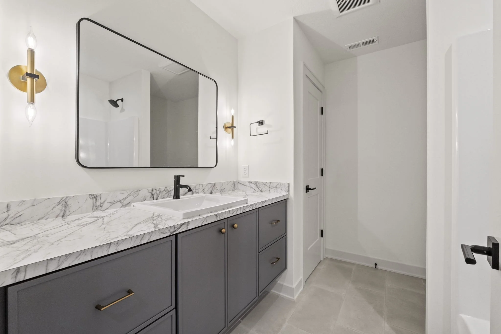 Modern bathroom with marble countertop, grey cabinets, and a large mirror above the sink.