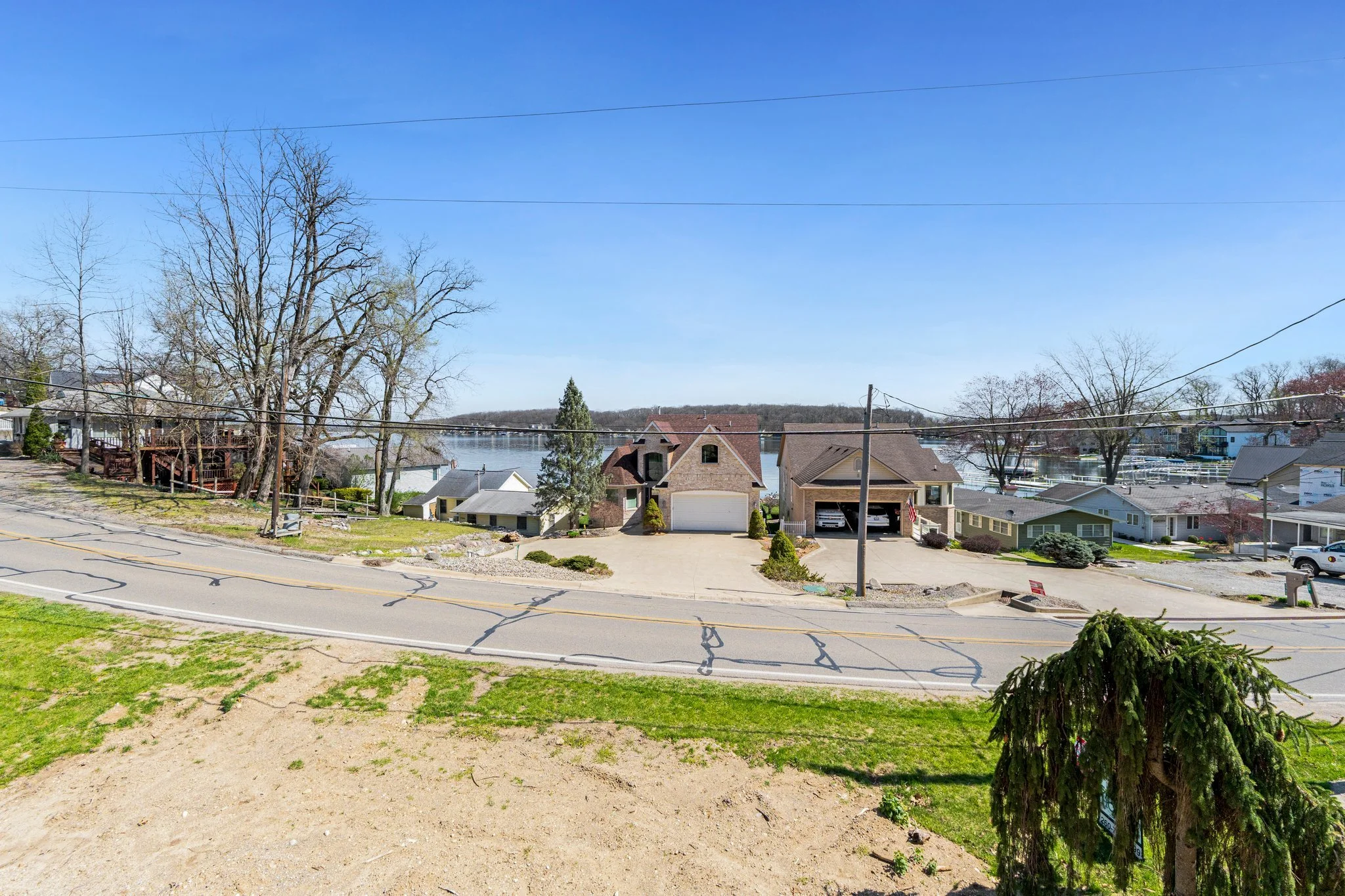 Residential neighborhood with lake view, houses, trees, and a clear blue sky.