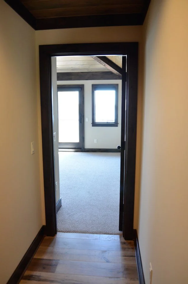View through a doorway into a room with dark trim, light carpet, and large windows.