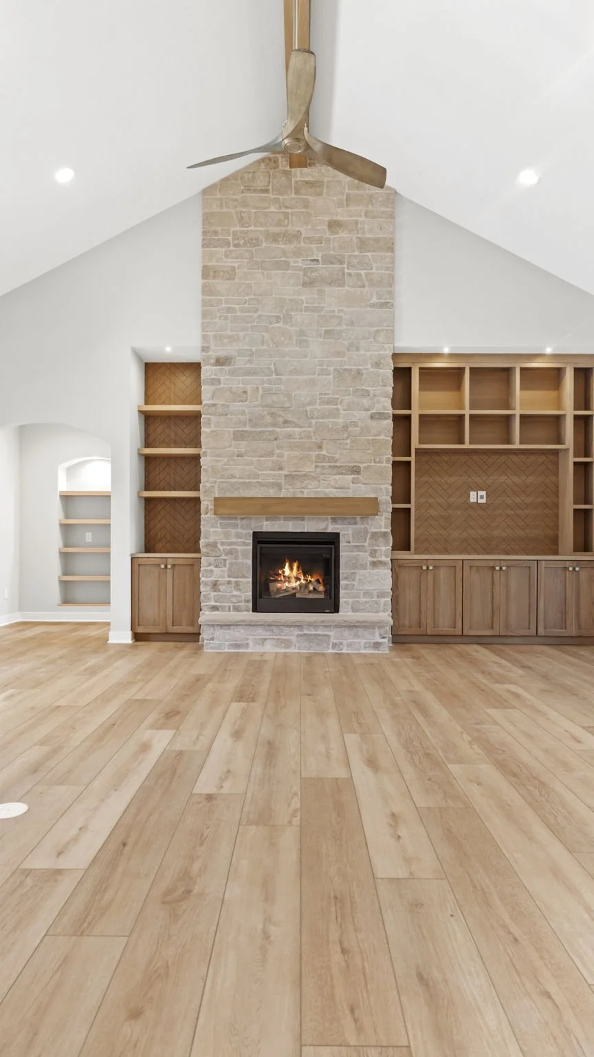 Living room with a central stone fireplace, built-in wooden shelves, and a ceiling fan with a wooden finish.