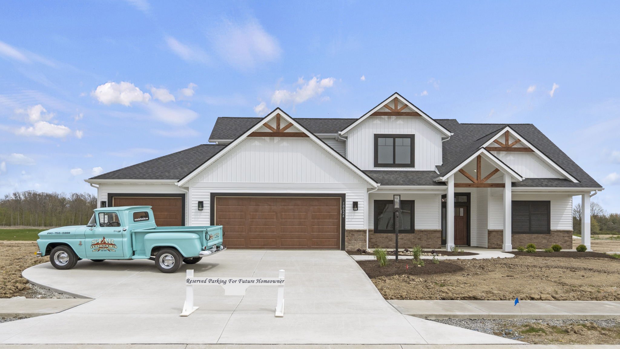 Newly constructed two-story house with white exterior and brown garage doors, a vintage blue pickup truck parked in the driveway, and a "Reserved Parking for Future Homeowner" sign in front.