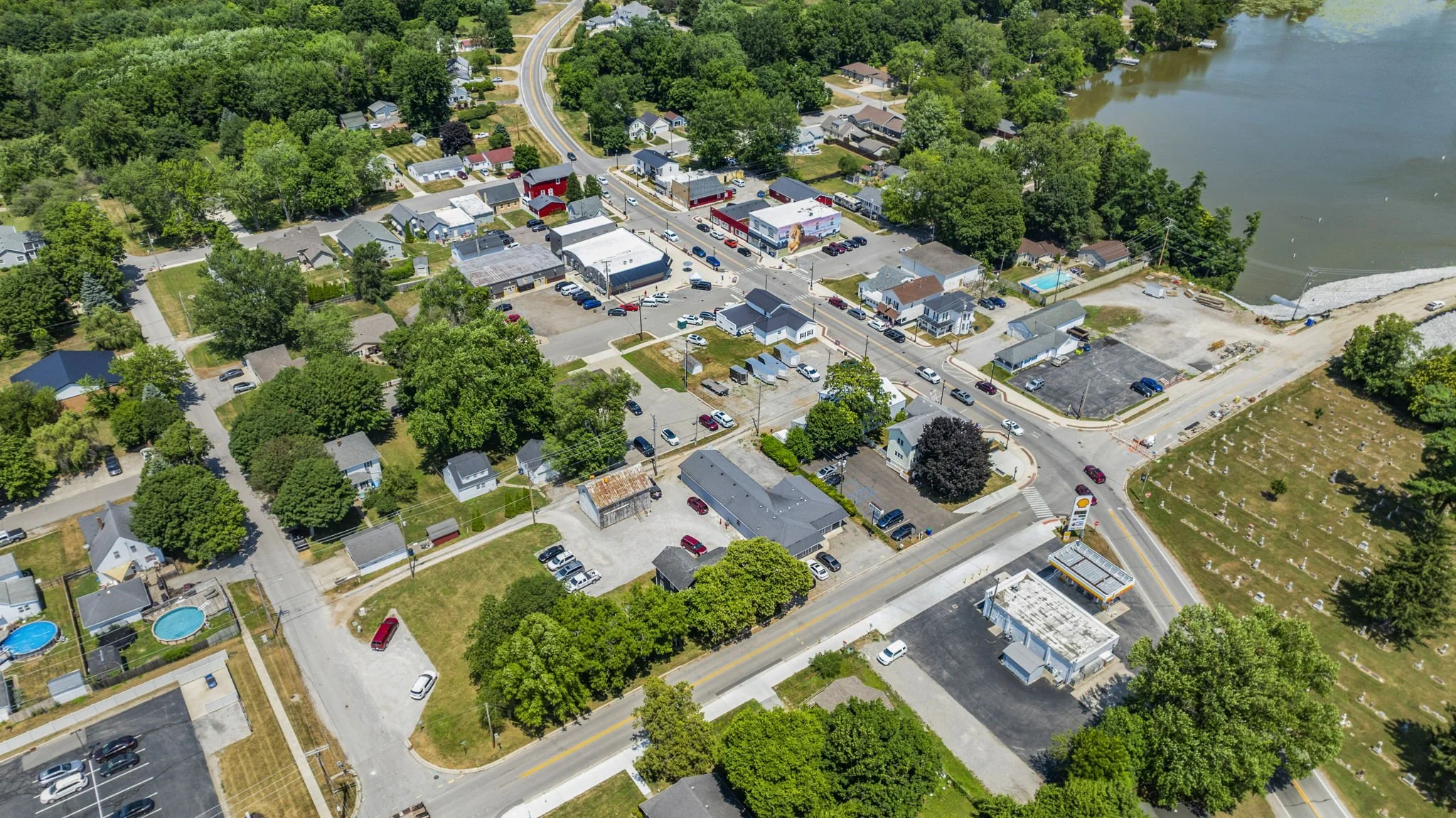 Aerial view of a small town with a main street, residential houses, trees, a river, and boat dock.