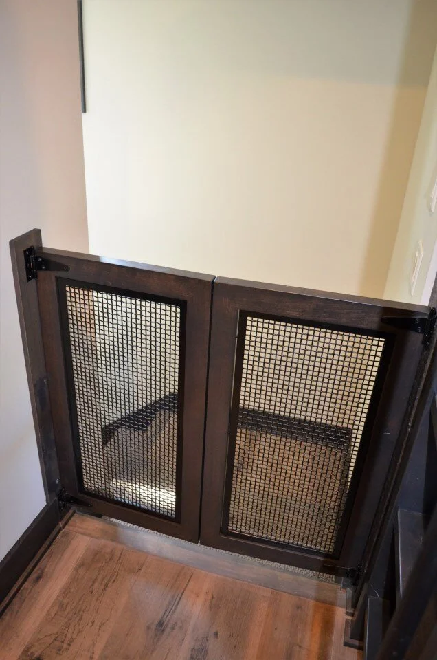 Two small wooden pet gates with wire mesh panels, installed in a doorway.
