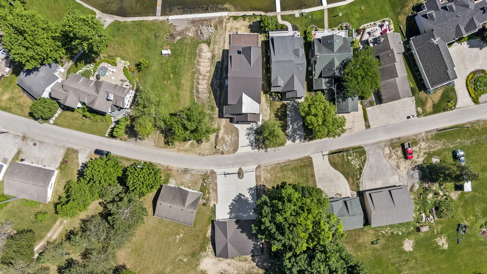 Aerial view of a residential neighborhood showing houses, trees, and streets with vehicles parked.