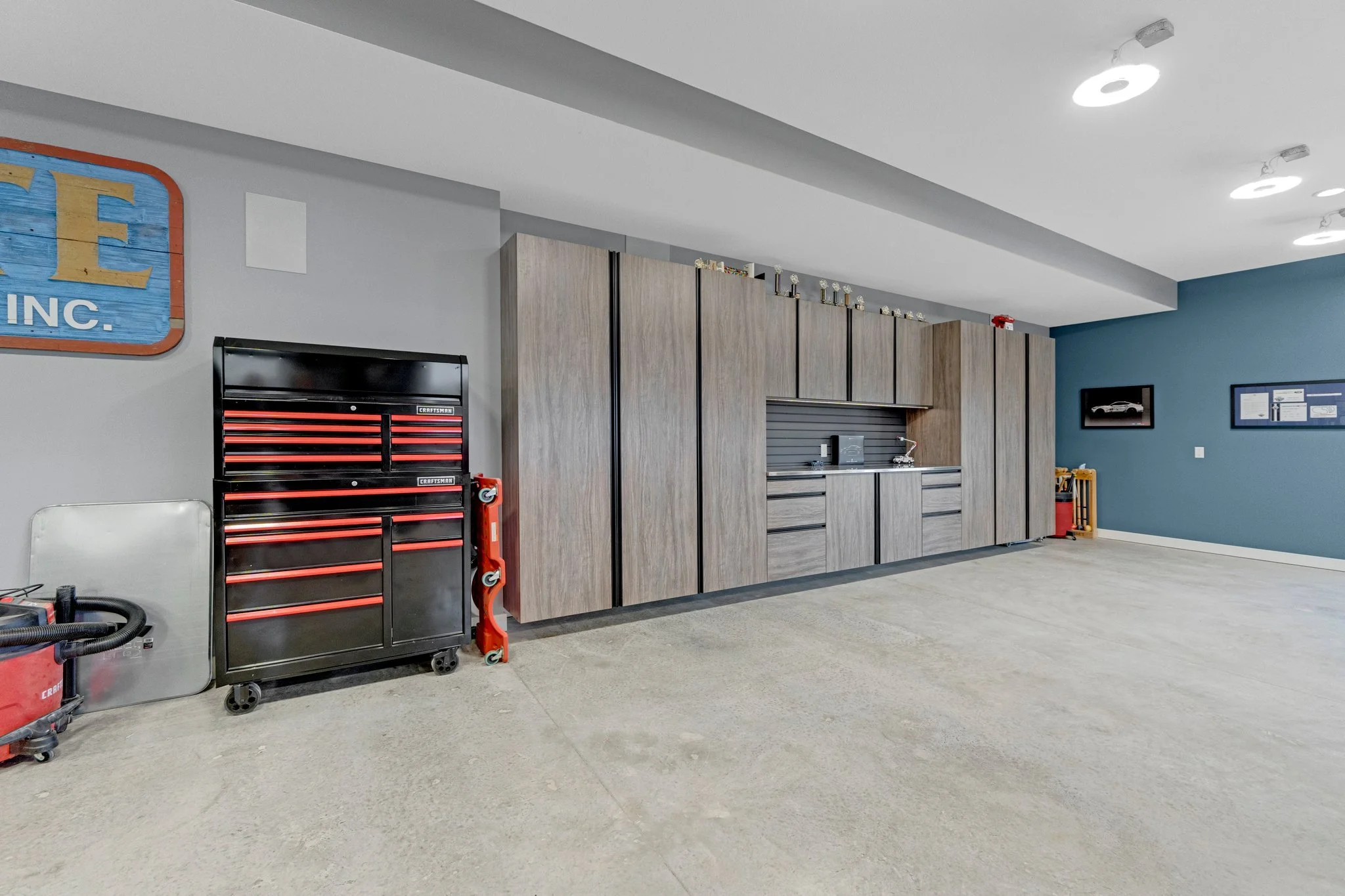 Garage or workshop with built-in cabinetry, a black and red tool chest, and framed pictures on the wall.