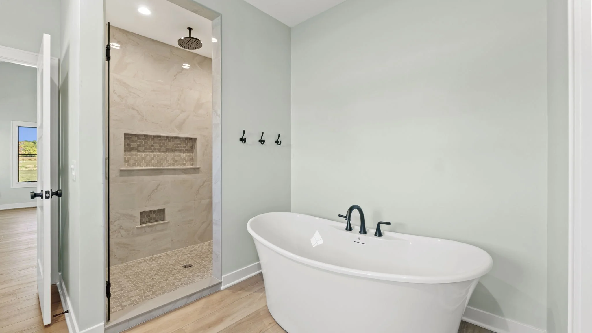 Modern bathroom featuring a freestanding bathtub and a walk-in shower with beige tile walls and a niche