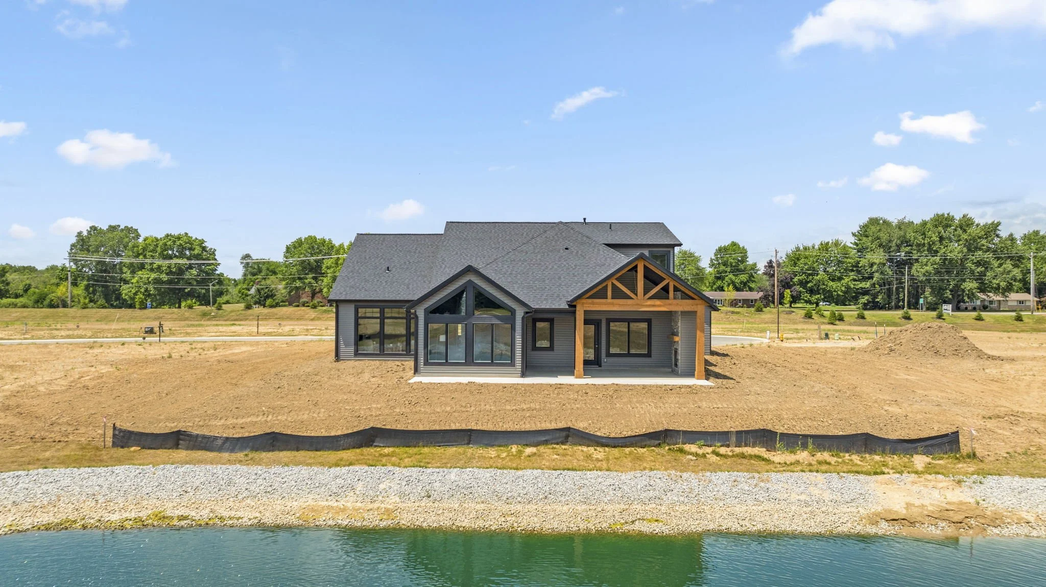 New house under construction near a body of water with a clear blue sky.