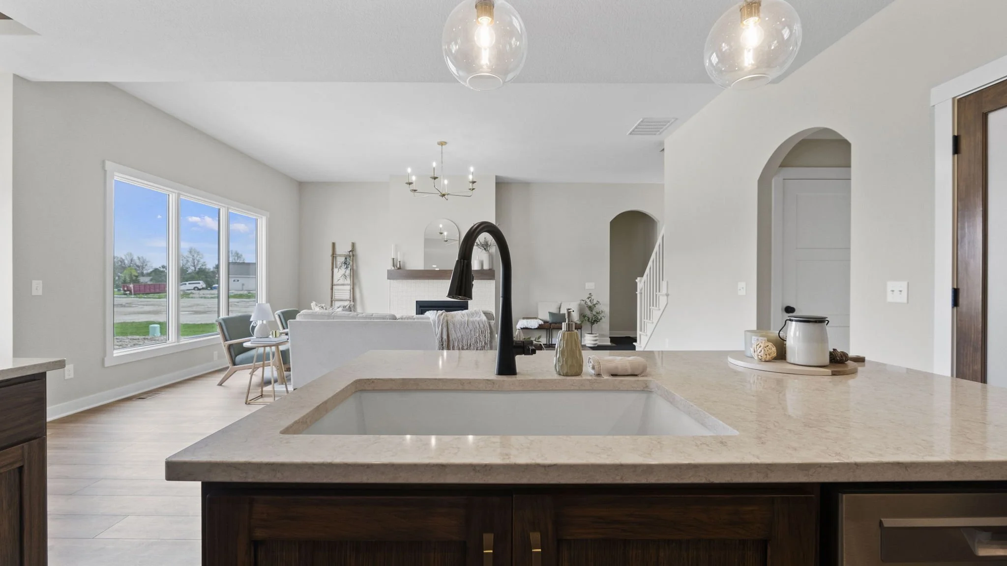 Modern open-concept kitchen and living area with large windows, white walls, and minimalist decor.