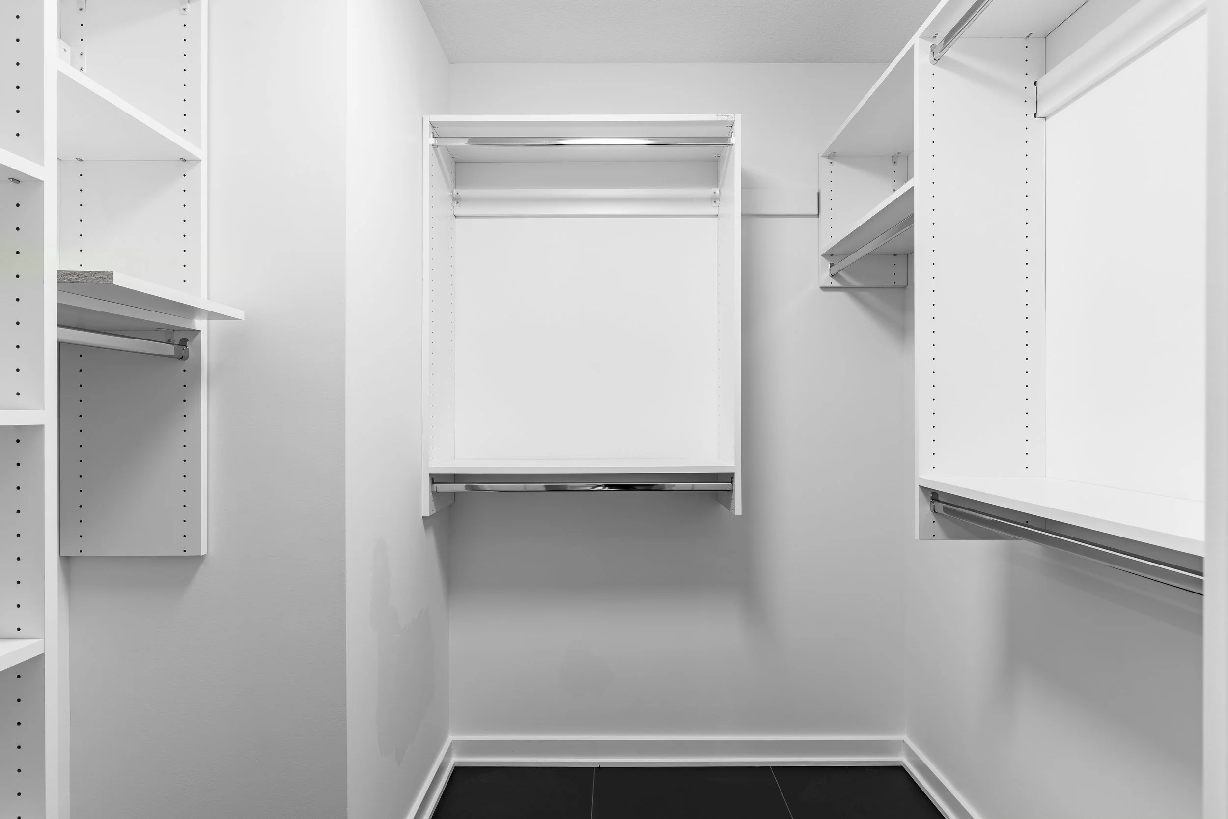 Empty white walk-in closet with built-in shelves and hanging rods