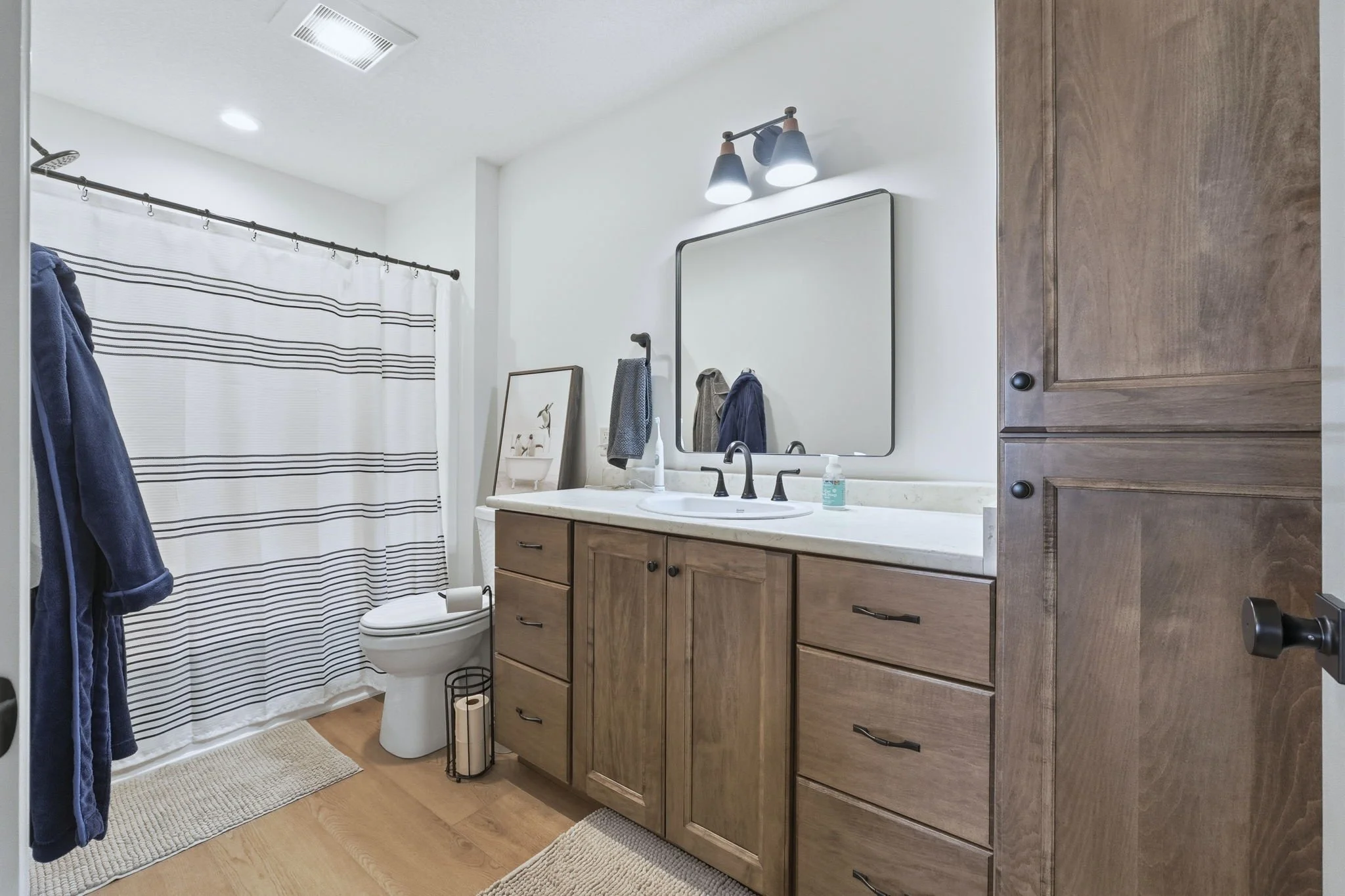 Clean bathroom with wooden vanity, large mirror, and striped shower curtain